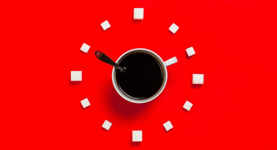 Black Coffee with Sugar Cubes circling the white cup on a red background