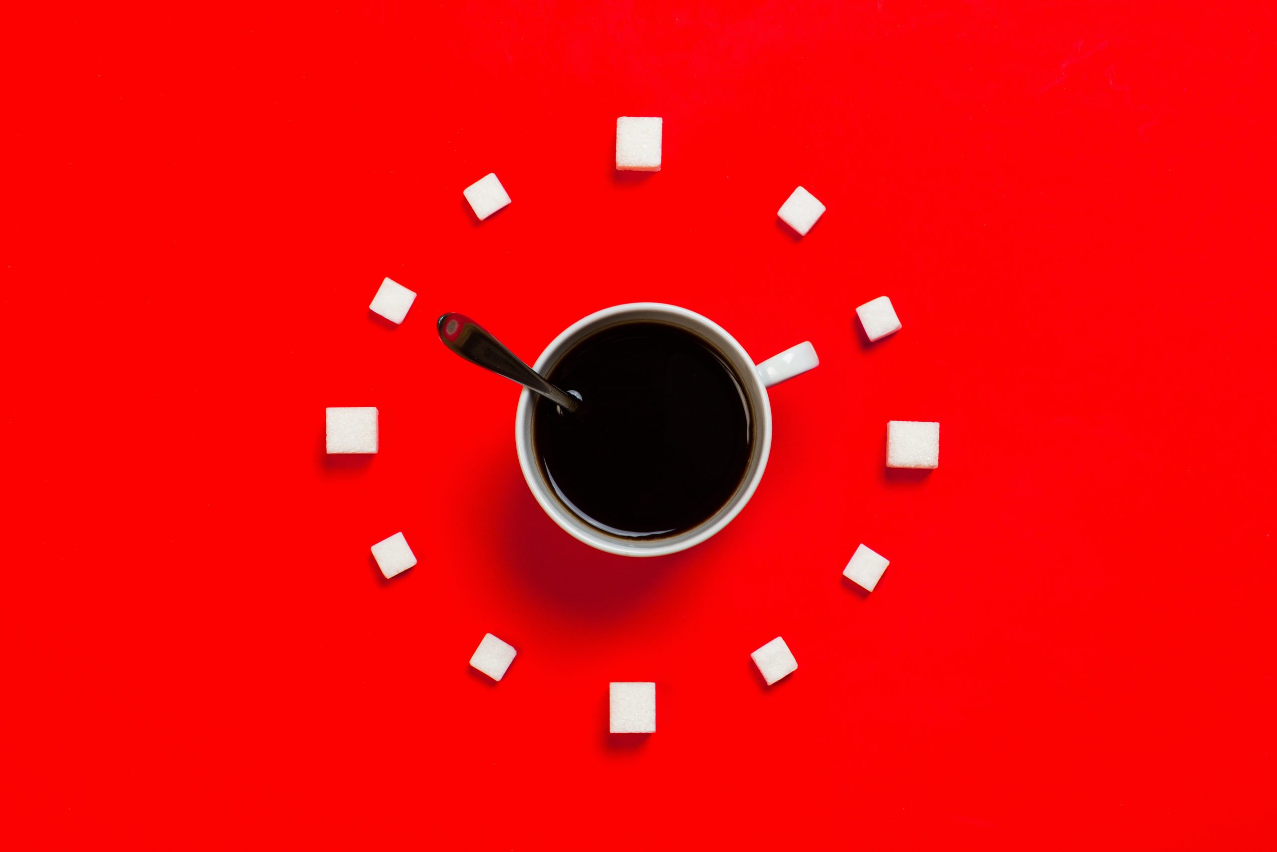 Black Coffee with Sugar Cubes circling the white cup on a red background
