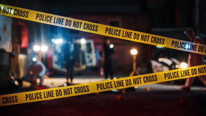 Two police line tapes block a crime scene setting at night wondering what the true crime stories behind this is